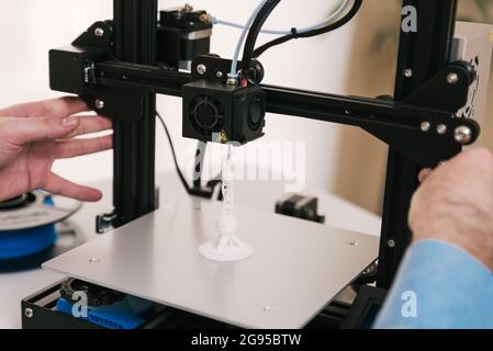 Young engineer in the lab adjusting a 3D printer's components Stock Photo