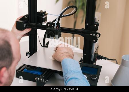 Young engineer in the lab adjusting a 3D printer's components Stock Photo