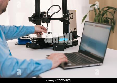 Young engineer in the lab adjusting a 3D printer's components Stock Photo