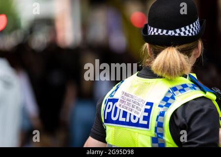 Manchester, UK. 24th July, 2021. An anti COVID19 vaccination sticker is placed onto a GMP police officers back during a demonstration. Hundreds of protesters against the lockdowns descend on the city. People march through city for a global Worldwide Rally For Freedom demonstration. Credit: Andy Barton/Alamy Live News Stock Photo
