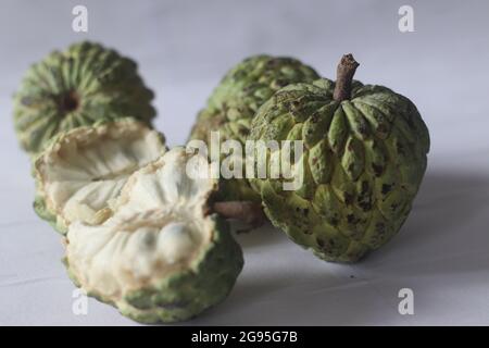 Cherimoya is a green, cone-shaped fruit with leathery skin and creamy, sweet flesh. It is also known as custard apple. The fruits vary in shape, heart Stock Photo