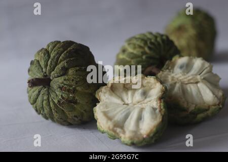 Cherimoya is a green, cone-shaped fruit with leathery skin and creamy, sweet flesh. It is also known as custard apple. The fruits vary in shape, heart Stock Photo