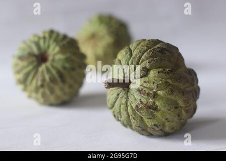 Cherimoya is a green, cone-shaped fruit with leathery skin and creamy, sweet flesh. It is also known as custard apple. The fruits vary in shape, heart Stock Photo