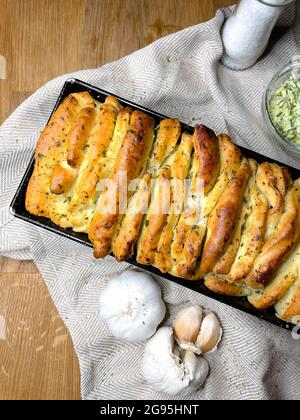 Vertical shot of freshly baked garlic bread on a wooden surface Stock Photo