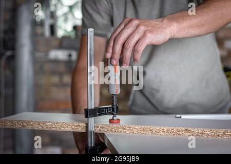 Carpenter doing wood work using clamping hand tool in his workshop. Stock Photo