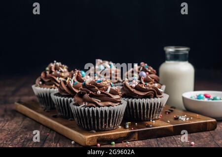Chocolate cupcakes with sprinkles on wooden board Stock Photo