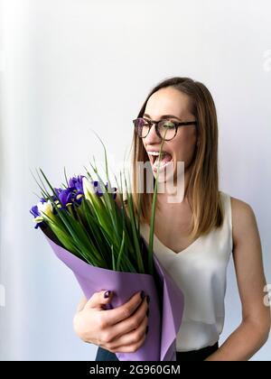 Surprised woman with glasses looking at a bouquet of irises Stock Photo