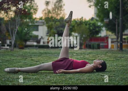 Hispanic young woman practices ballet with pointe shoes in a park. Stock Photo