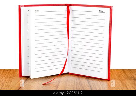 Open red lined notebook standing on a wooden table, isolated on a white background. Stock Photo