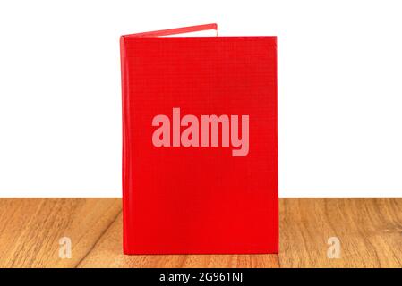 Slightly opened red lined notebook standing on a wooden table, isolated on a white background. Stock Photo