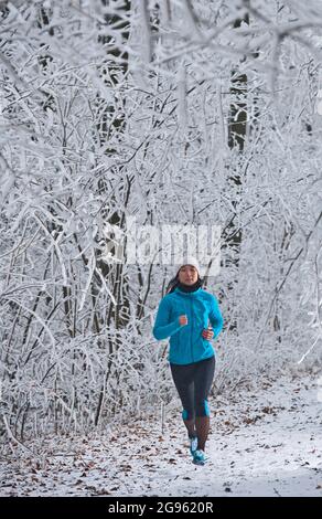 woman running through frosty German forest in Lower Saxony Stock Photo