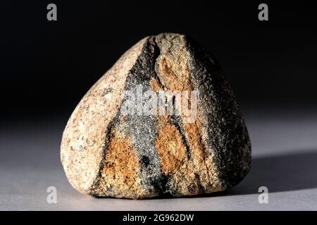 Single stone with red and brown geological pattern isolated on grey background Stock Photo