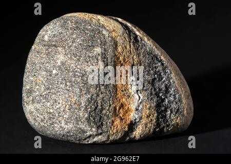 Single stone with red and brown geological pattern isolated on black background Stock Photo