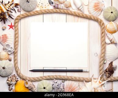 A white sheet of paper with a pencil surrounded by rope and many shells and sea urchins. Marine thematic flatlay Stock Photo