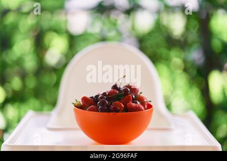 Plate with cherries and strawberries stands on the table on the balcony Stock Photo
