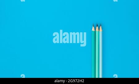 Tree pencils on blue background, minimalistic concept. Copyspace and top view Stock Photo