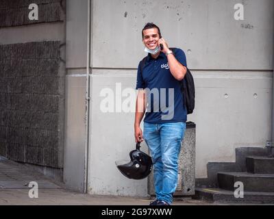 Medellin, Colombia - July 21 2021: Latin Men in Shirt and Jeans and Mask on his Chin Talks on the Phone Standing on the Sidewalk Happily Stock Photo