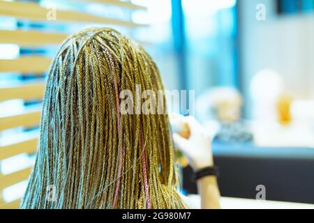 hair with pigtails, head of girl or young woman, seen from behind, stands inside a public place, in the blur her hands with something to eat Stock Photo