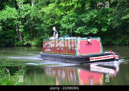 A canal barge on the Bridgewater Canal,  Sale, Trafford, Greater Manchester, England, with a man steering it. Stock Photo