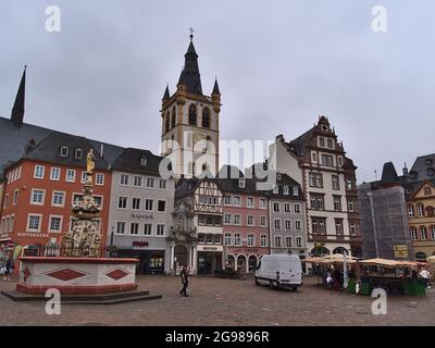 View of marketplace Hauptmarkt with weekly market in the historic center of Trier on cloudy summer day with fountain and the steeple of Catholic. Stock Photo
