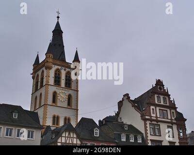 Historic old buildings at square Hauptmarkt in city Trier, Rhineland-Palatinate, Germany with steeple of Catholic church St. Gangolf on cloudy day. Stock Photo