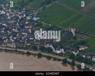 View of small village Neef, Rhineland-Palatinate, Germany, located on the riverbank of Moselle river, with church, old buildings and green hills.