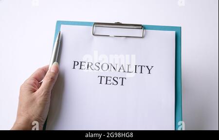 Woman holding a pen with personality test on clipboard. On white background. Stock Photo