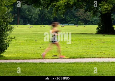 Munich, Germany. 25th July, 2021. A woman jogs through the English Garden, located in the heart of the Bavarian capital. Credit: Peter Kneffel/dpa/Alamy Live News Stock Photo