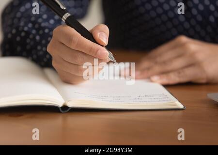 Close up woman taking notes in notebook, holding pen Stock Photo