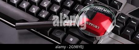 Black keyboard from a computer with a magnifying glass. Enter and switch keys. Tool. Press. Red enter button enlarged with magnifying glass. Stock Photo