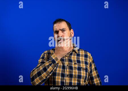 Handsome middle age senior man with grey hair over isolated blue background with hand on chin thinking about question, pensive expression. Smiling and Stock Photo