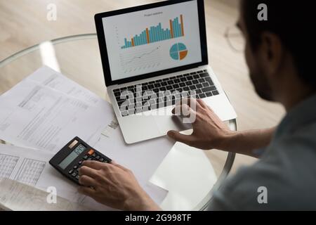 Closeup man verifies data financial reports with graphs on computer Stock Photo