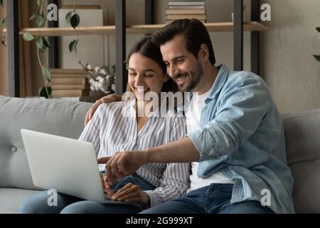 Couple sit on sofa enjoy easy purchasing online using laptop Stock Photo