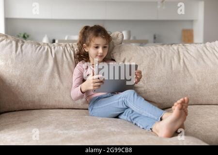 Small ethnic girl child use tablet at home Stock Photo