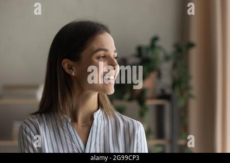 Headshot portrait smiling woman daydreaming standing indoors looking away Stock Photo