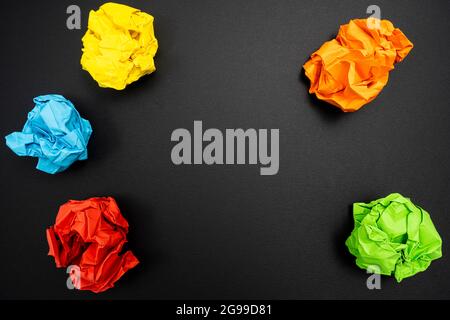 a few sheets of crumpled colored paper on a black surface Stock Photo