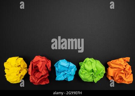 a few sheets of crumpled colored paper on a black surface Stock Photo