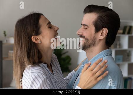 Overjoyed couple looking at each other laughing hugging at home Stock Photo