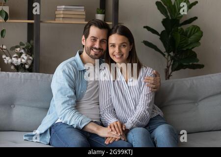 Beautiful married couple sit on sofa smile look at camera Stock Photo