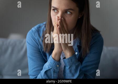 Female sit indoor looks into distance feels horrified by news Stock Photo