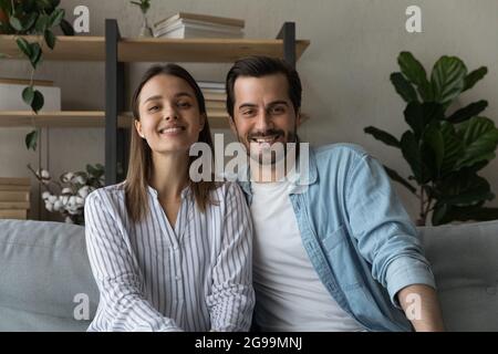 Beautiful married couple sit on sofa smile look at camera Stock Photo