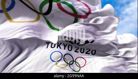 Tokyo, Japan, July 2021: Tokyo 2020 olympic flag waving with the Olympic flag blurred in the foreground. Selective focus. Tokyo 2020 olympics games we Stock Photo