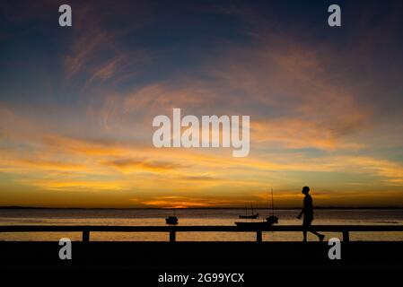 Silhouette of a man at sunset on the edge of the Ribeira neighborhood in Salvador, Bahia, Brazil. Stock Photo