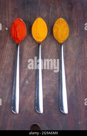 Indian Colourful Spices Also Know as Red Chilli Powder, Turmeric Powder, Coriander Powder, Mirchi, Mirch, Haldi, Dhaniya Powder Isolated on wooden Bac Stock Photo