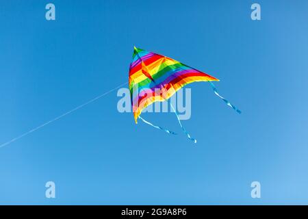 a kite in rainbow colors on a blue sky background Stock Photo