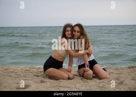 Young women hugging on beach near sea Stock Photo