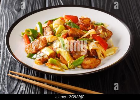 Twice cooked pork is Szechuan style stir-fry pork belly cooked in sauce and vegetables closeup in the plate on the wooden table. Horizontal Stock Photo