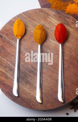 Indian Colourful Spices Also Know as Red Chilli Powder, Turmeric Powder, Coriander Powder, Mirchi, Mirch, Haldi, Dhaniya Powder Isolated on wooden Bac Stock Photo