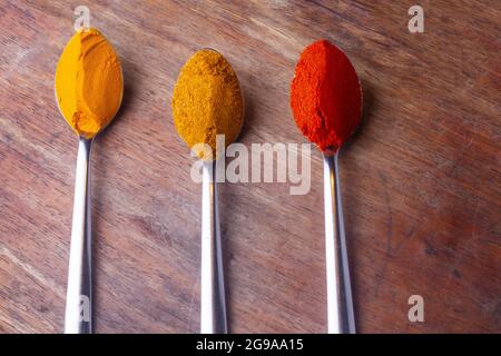 Indian Colourful Spices Also Know as Red Chilli Powder, Turmeric Powder, Coriander Powder, Mirchi, Mirch, Haldi, Dhaniya Powder Isolated on wooden Bac Stock Photo