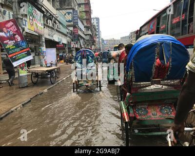 street is full of water and Rickshaw  running on the road . waterlogging on capital city . Stock Photo